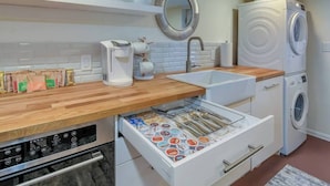 Une cuisine moderne dotée d’un plan de travail en bois, d’une machine à café, d’un évier, d’un lave-vaisselle et d’un four encastré.