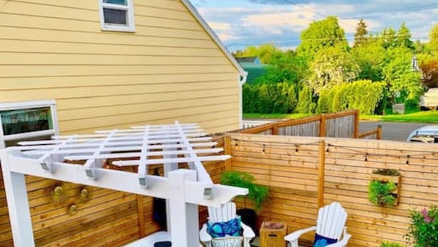 Un jardin avec un jacuzzi, deux fauteuils Adirondack, une terrasse en bois et une pergola.