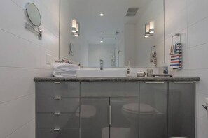 A modern bathroom with a large mirror, a sink, and a toilet. - Large eclectic 1 BR above restaurant 15 min to PDX (Camas)