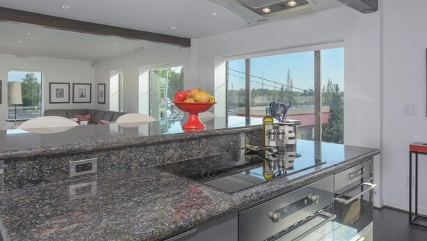 Una cocina moderna con encimeras de granito, electrodomésticos de acero inoxidable y un amplio ventanal con vistas al exterior.