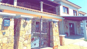 Une maison à deux étages avec une façade en pierre, un portail en métal et un balcon.