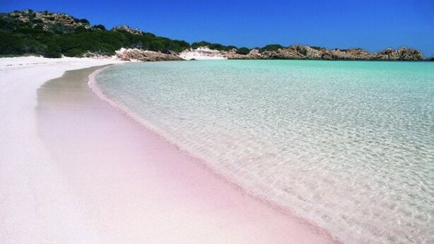 Une plage à l’eau turquoise et au sable blanc.