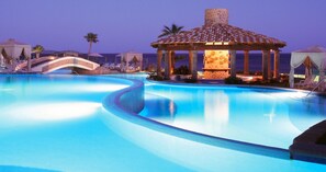 A swimming pool with a gazebo, palm trees, and a bridge.