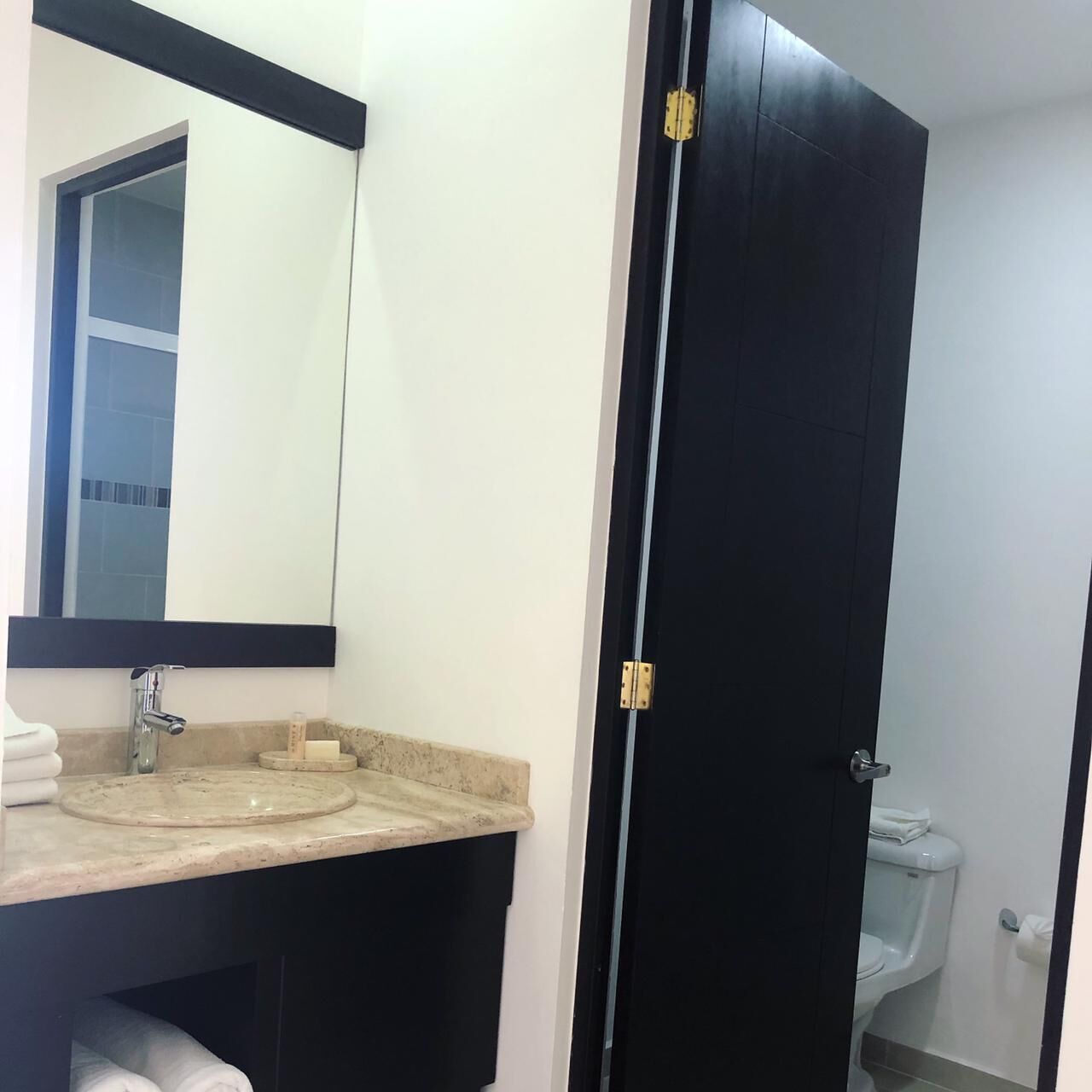 Un baño con lavamanos, espejo e inodoro.