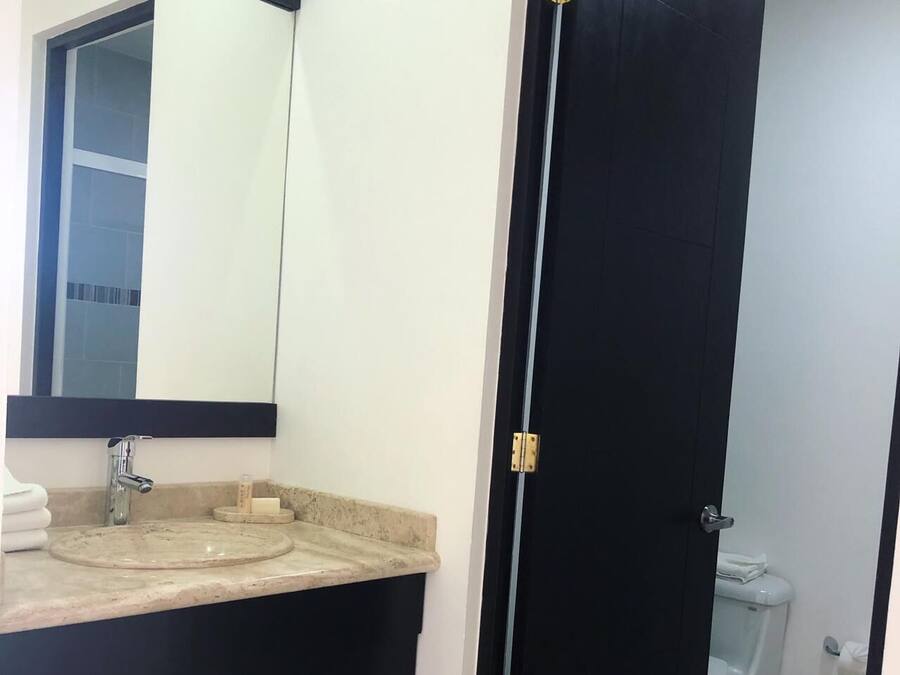 Un baño con lavamanos, espejo e inodoro.