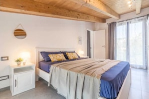 Un dormitorio con cama, mesitas de noche, un espejo y una ventana con cortinas.