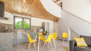 A modern kitchen with a curved ceiling, a dining area with yellow chairs, and a living room with a black sofa. - Detached villa with outdoor hot tub, swimming pool and lawn  (La Spezia)