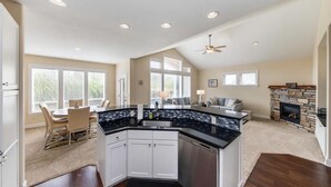 Una cocina amplia con una isla central, un comedor con mesa y sillas, y una sala de estar con chimenea.