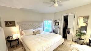 Une chambre à coucher avec un grand lit, une table de chevet, une lampe, une plante en pot et une armoire.
