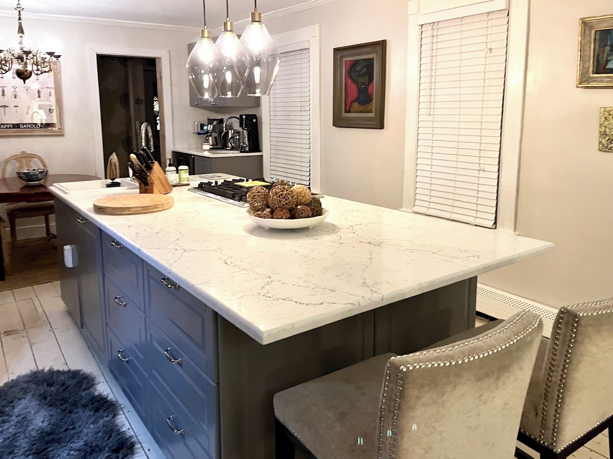 A kitchen with a marble countertop, a bowl of decorative items, and a chandelier.