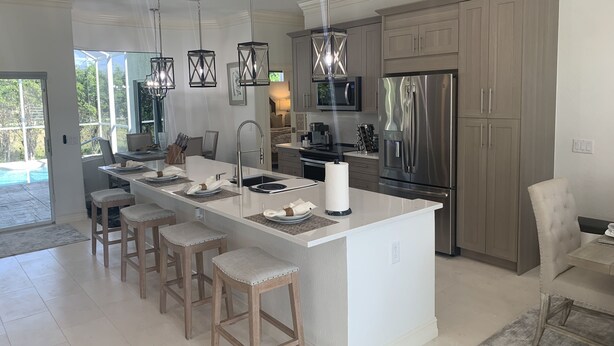 Una cucina moderna con isola centrale, elettrodomestici in acciaio inossidabile e illuminazione a sospensione.