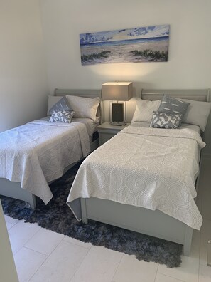 A double bed with a patterned bedspread, a bedside table with a lamp, and a painting above the bed. - AAA - MARCO ISLAND LUXURY HOME, WALK TO THE BEACH. (Marco Island)