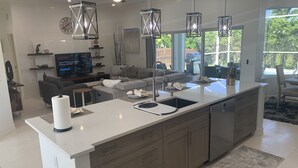 Una cucina moderna con un'isola grande, elettrodomestici in acciaio inossidabile e illuminazione a sospensione.