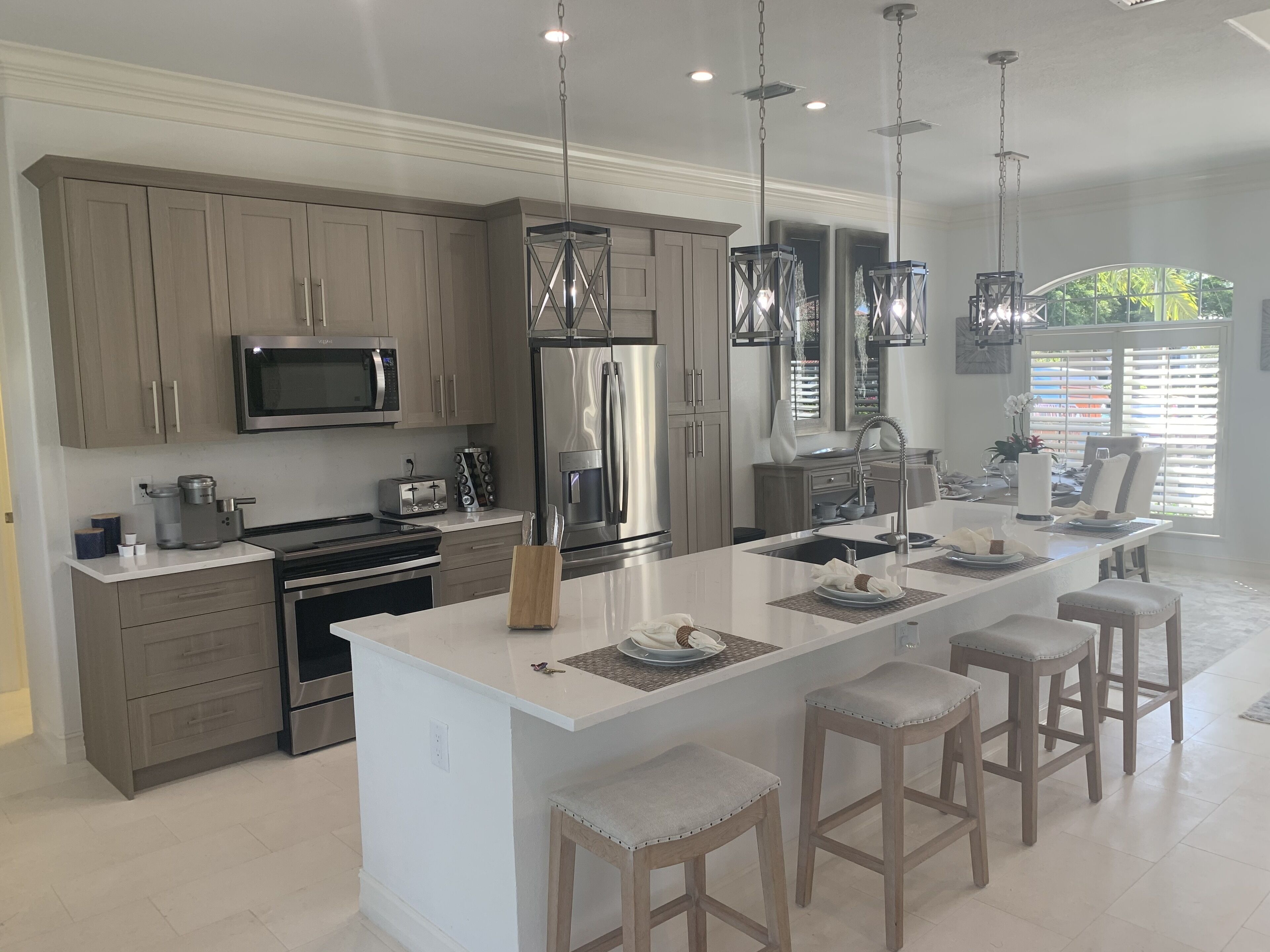 A modern kitchen with a central island, stainless steel appliances, and pendant lighting.
