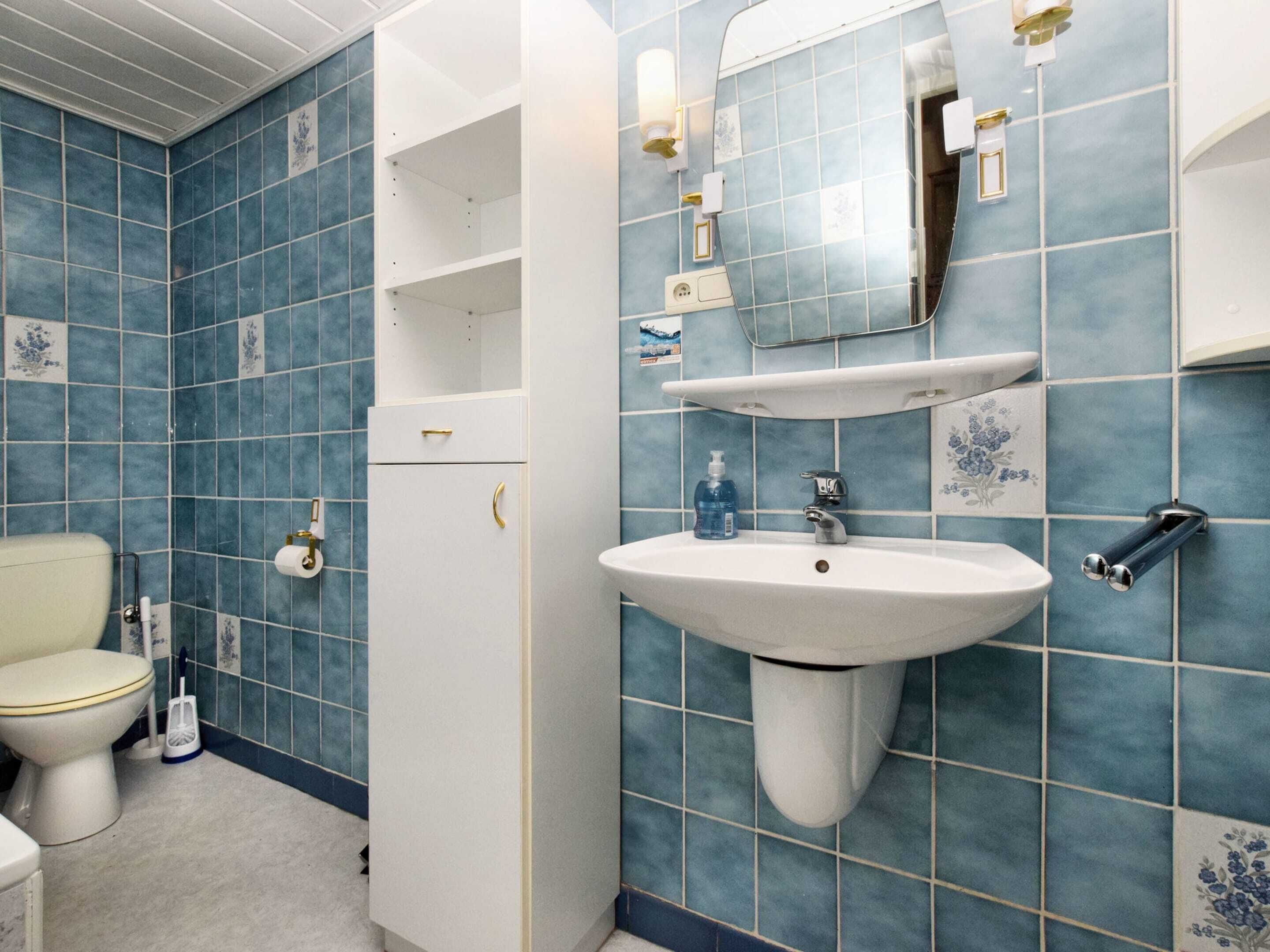 Une salle de bain avec des toilettes, un lavabo et un miroir.