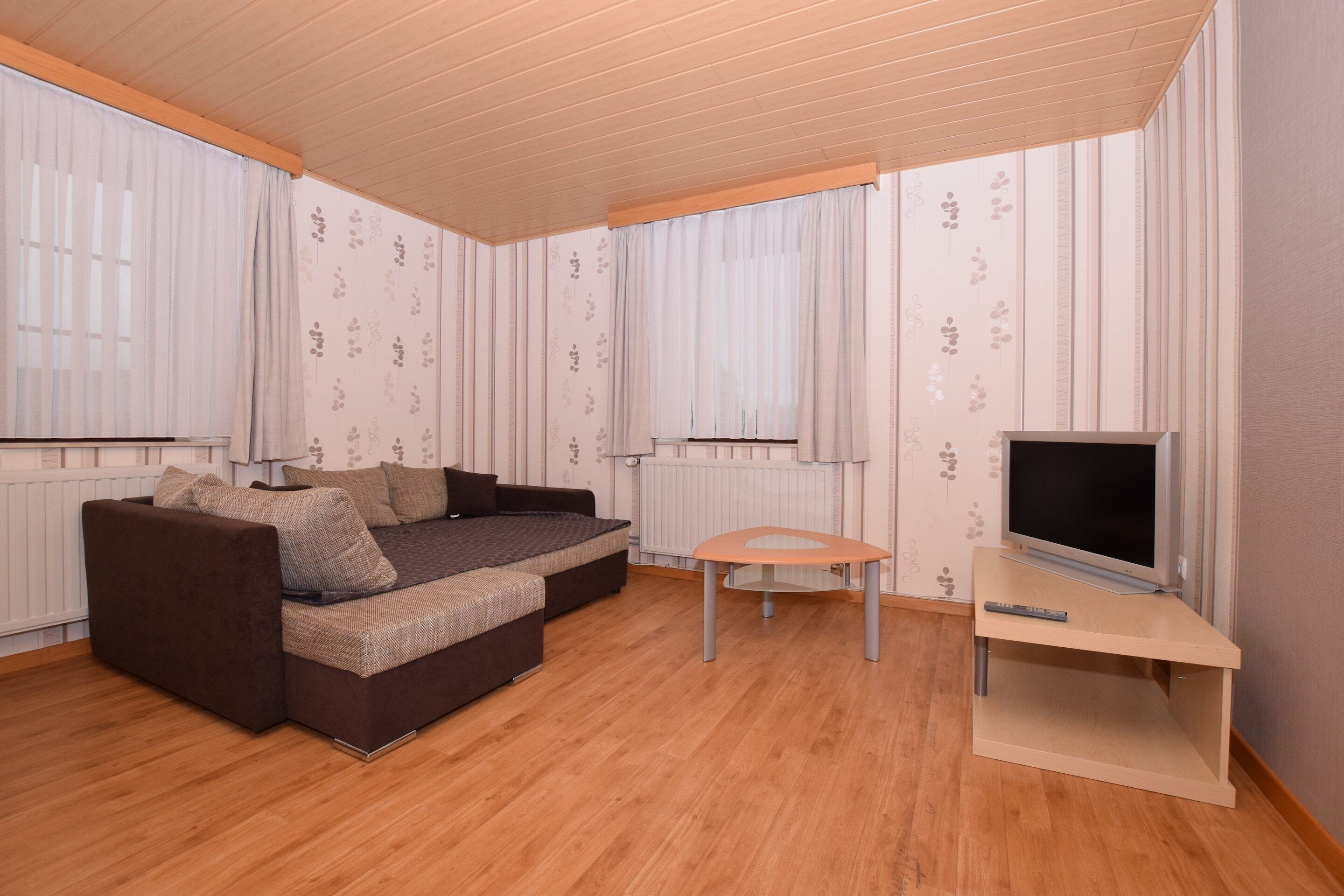 Una sala de estar moderna con un sofá modular, una mesita y un televisor sobre un mueble.