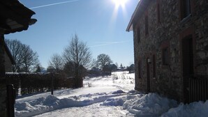 Una carretera rural cubierta de nieve, flanqueada por edificios de piedra.