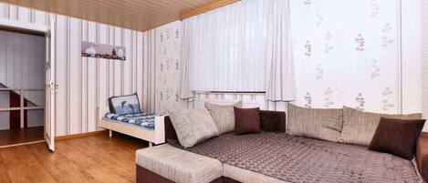 Un dormitorio con una cama grande, una mesita de noche pequeña, un armario y una ventana con cortinas.