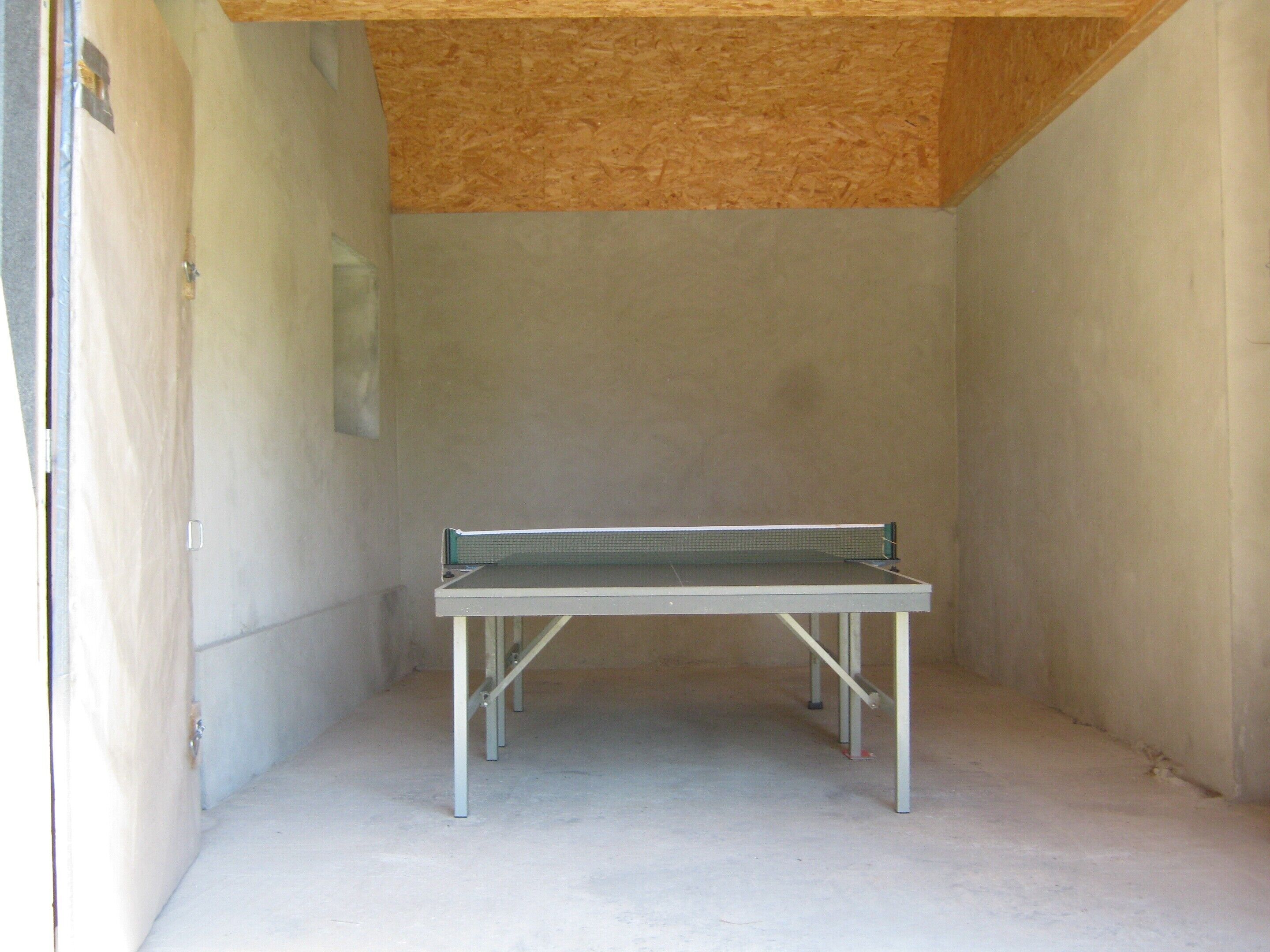 A ping pong table in a room with unfinished walls and a concrete floor.