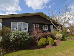 A modern two-story house with a dark exterior, large windows, and a well-maintained garden with various shrubs and a lawn. - Cozy Chalet With Pond, Malmedy (Malmedy)