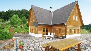 Une cabane en bois avec un patio en pierre, une table en bois et un banc.