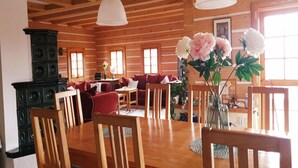 Un intérieur en bois avec un coin repas, des canapés rouges et un vase de fleurs.