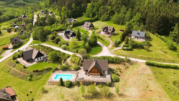 Un village rural dont les maisons sont entourées d’une végétation luxuriante et d’une forêt.