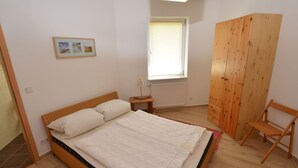 A bedroom with a single bed, a wooden wardrobe, a small bedside table, and a window with blinds. - Retreat With Garden Views (Dolní Lánov)