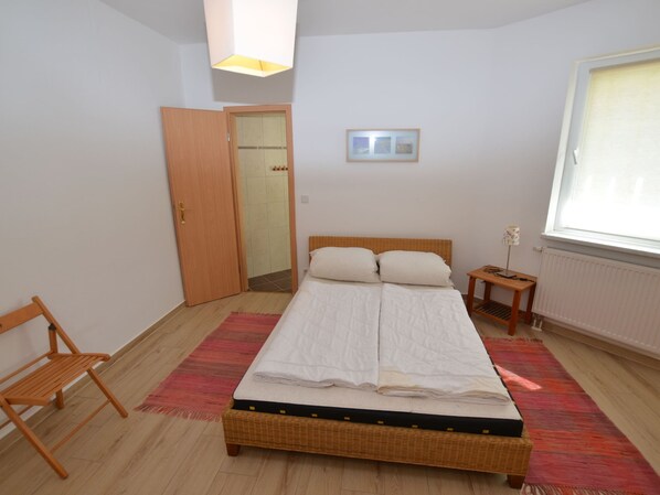 A bedroom with a bed, a chair, a bedside table, a radiator, and a window. - Retreat With Garden Views (Dolní Lánov)