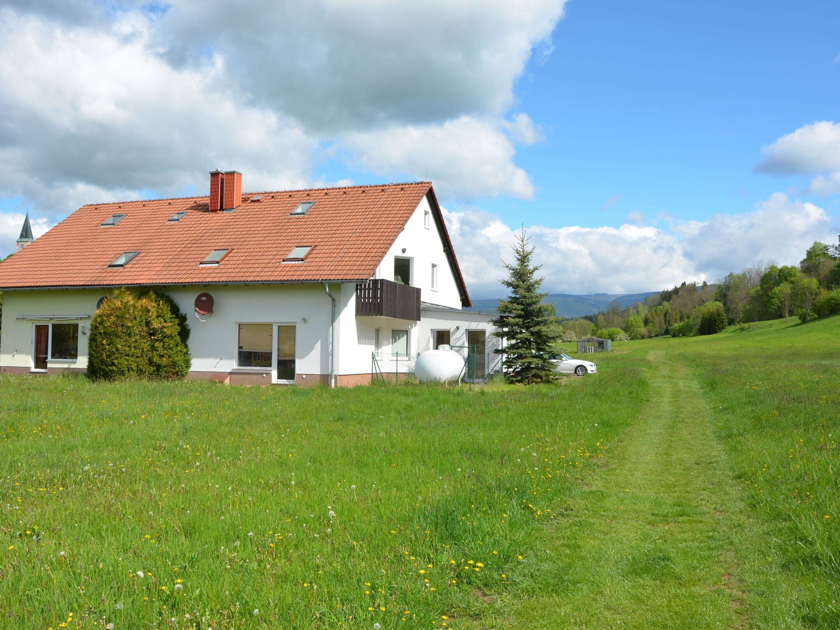 A two-story house with a red-tiled roof, a small attached garage, and a well-maintained lawn.
