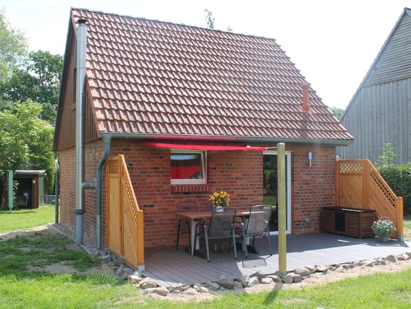 A small brick house with a tiled roof, a patio with outdoor furniture, and a wooden deck. - Lovely Holiday Home in Zierow With Terrace (Zierow)