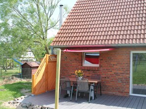 A brick house with a tiled roof, a wooden deck, and a dining table with chairs. - Lovely Holiday Home in Zierow With Terrace (Zierow)