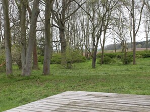 A wooden deck in a grassy area with trees and bushes. - Wohnung in Neuburg in der Nahe des Ostseestrandes (Neuburg)