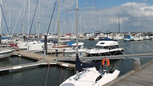 En marina med flere både i havnen, træpromenader og en klar himmel.