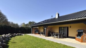 Una casa con patio, mobiliario exterior y un muro de piedra.