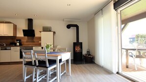 Una cocina moderna con armarios blancos, una mesa de comedor con sillas, un microondas integrado y un estufa de leña.