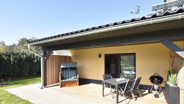 Un patio techado con una mesa y sillas, una parrilla y una mecedora.