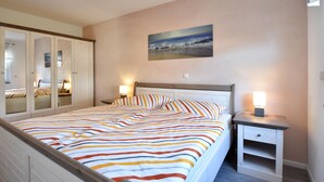 Un dormitorio con cama, mesitas de noche, armario y un cuadro en la pared.