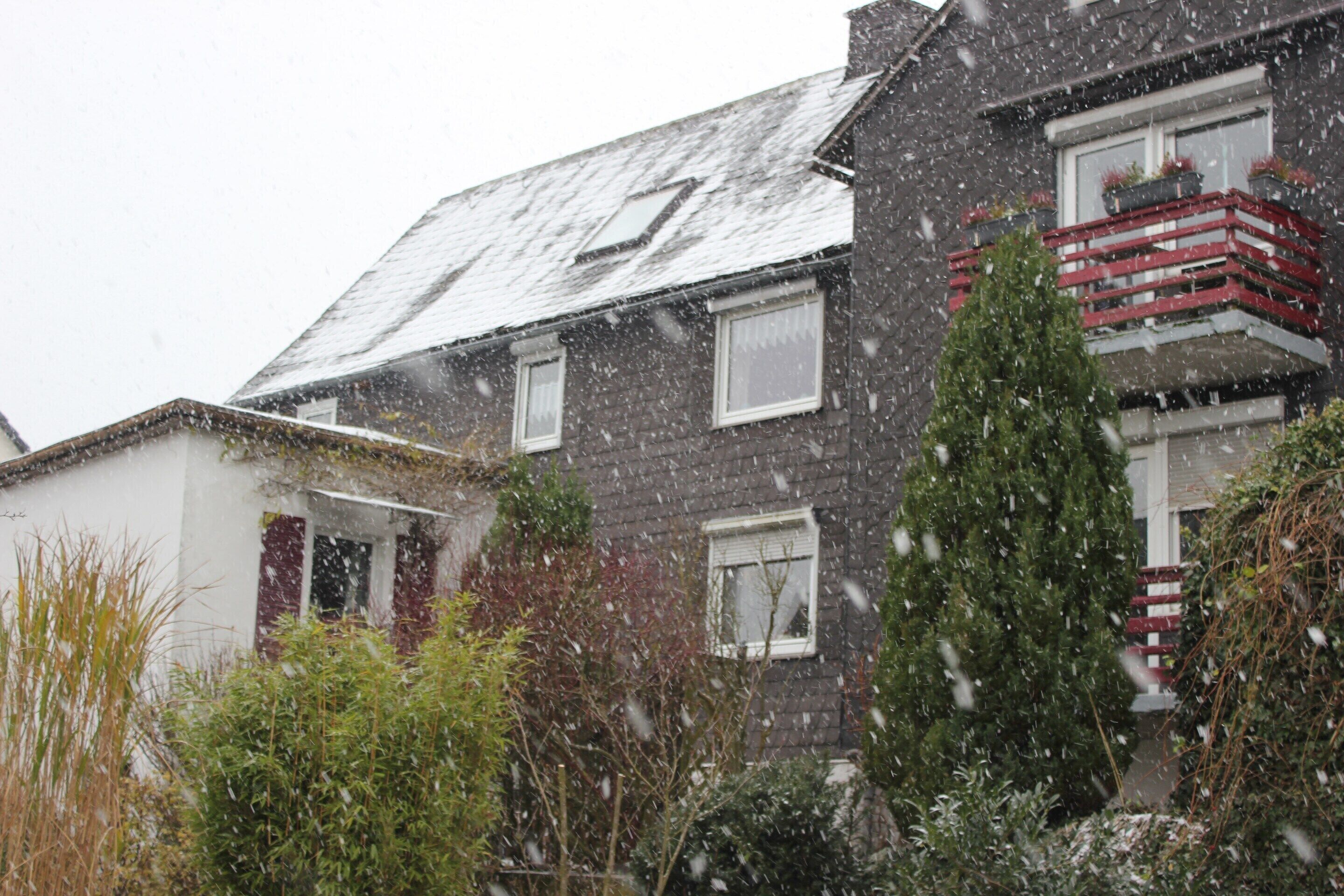 A two-story house with a sloped roof, visible windows, and a red balcony.