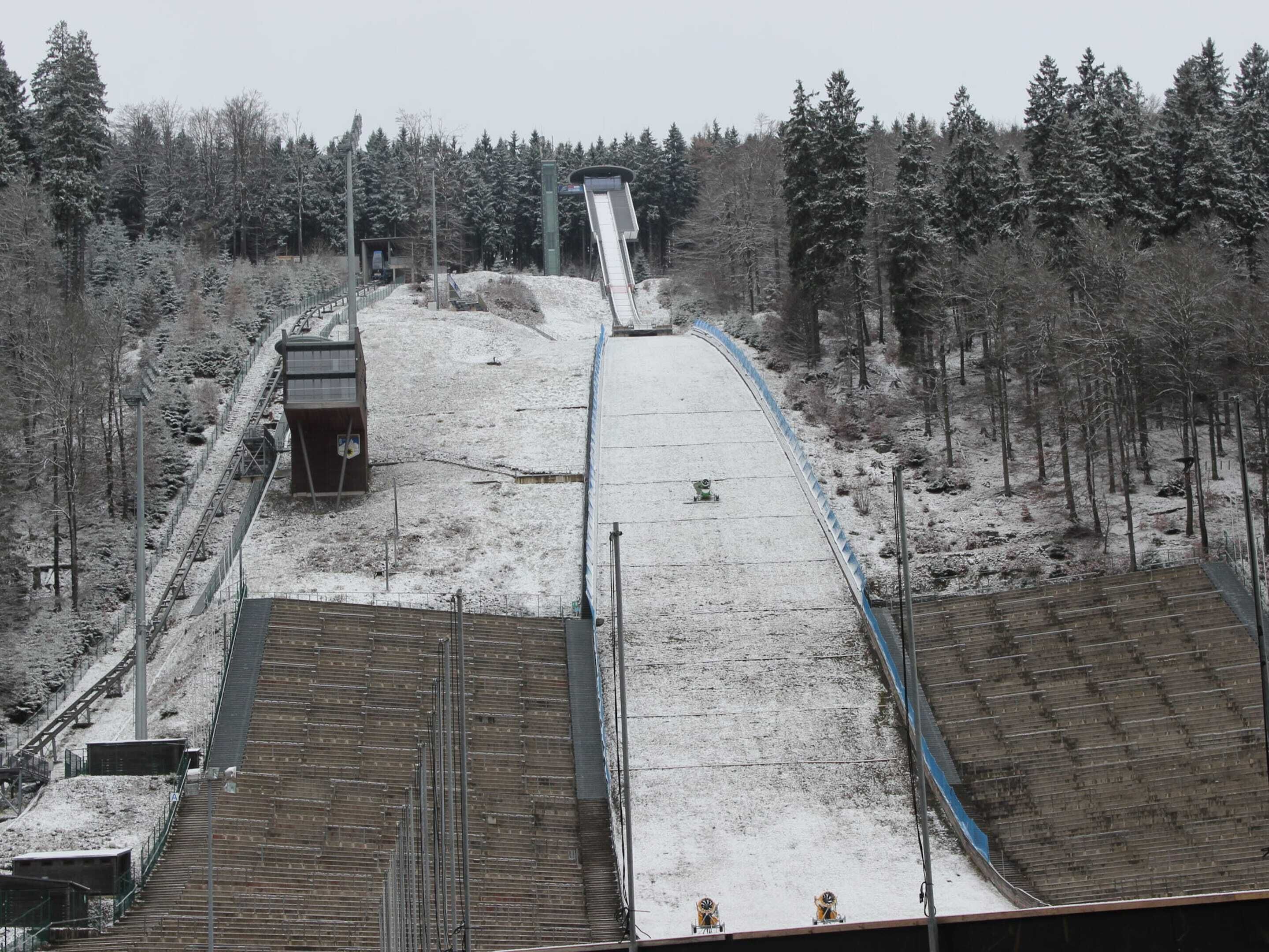 A snowy ski slope with a chairlift, surrounded by trees.