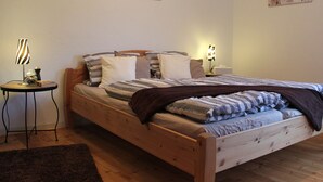 Un lit bien fait, avec une literie à rayures, deux tables de chevet avec des lampes et des œuvres d’art accrochées au mur au-dessus du lit.