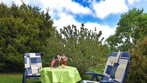 Un espace extérieur aménagé avec deux chaises et une table, entouré de verdure et d’arbres.