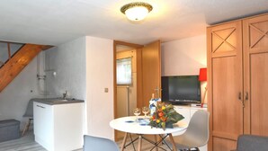 Un espace de vie compact comprenant une kitchenette, un coin repas et un téléviseur.