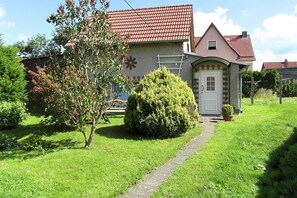 A house with a red-tiled roof, a small porch, and a garden with a pathway leading to the front door. - Holiday Home With Terrace in the Harz Mountains (Harzgerode)