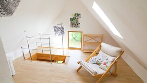 Ein geräumiges Schlafzimmer im Loft-Stil mit Holzboden, einem hölzernen Bettgestell, einem Holzstuhl und einem Oberlicht.