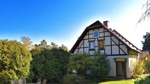 Ein traditionelles Fachwerkhäuschen mit gepflegtem Rasen und einer Sitzgelegenheit im Freien.