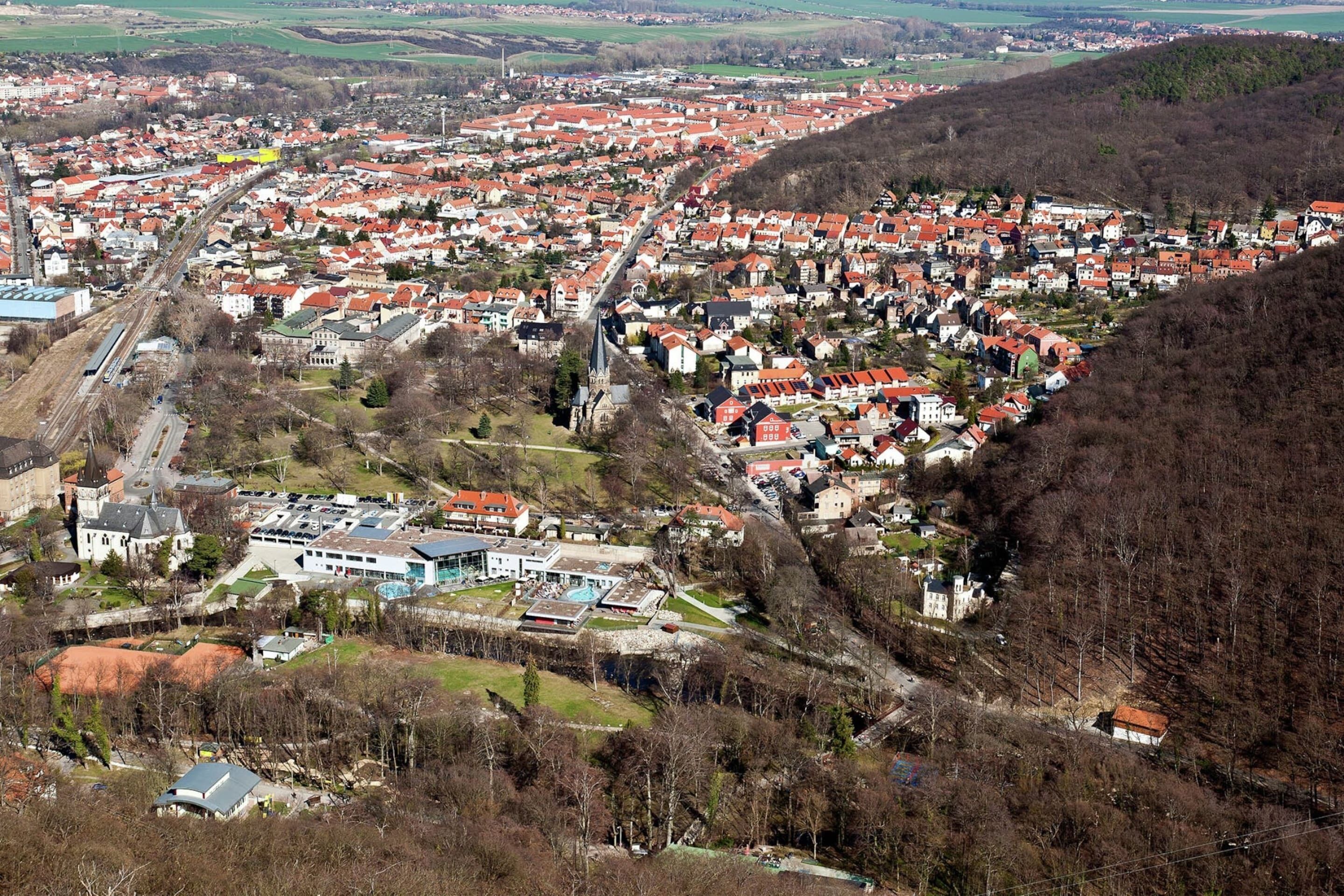 Vista aérea de un pueblo con casas de techo rojo, una iglesia y un edificio grande con techo verde.