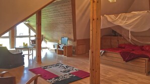 A spacious loft bedroom with a wooden floor, a bed with a canopy, a desk with a computer, and a chair. - Alpine Stay in Herrischried (Herrischried)