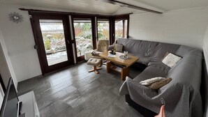 Ein gemütlicher Wohnbereich mit grauem Sofa, einem Holztisch und einem beigefarbenen Sessel.