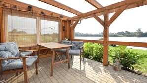 Une terrasse en bois avec une table et des chaises, donnant sur un lac.